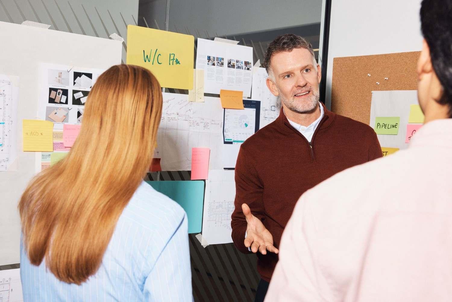 Coworkers sharing ideas in front of a planning board