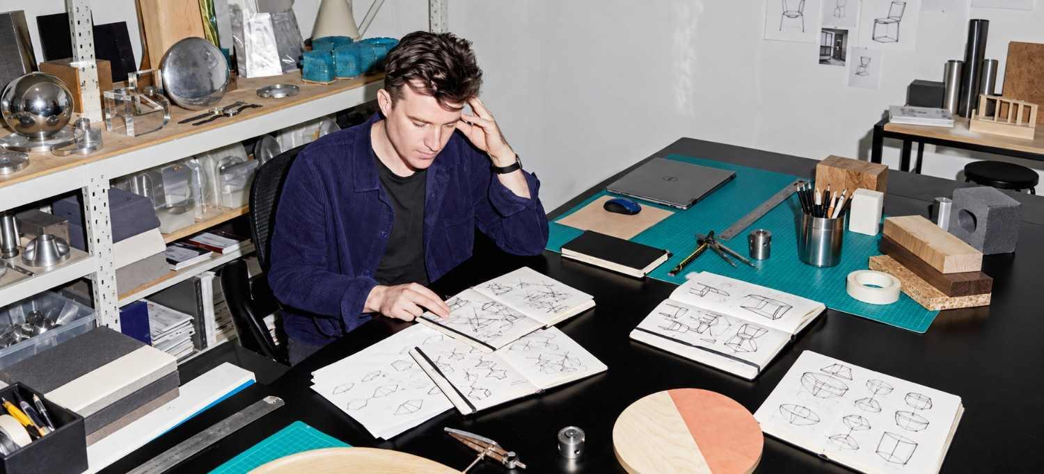 A designer reviewing sketches and notes at a workbench
