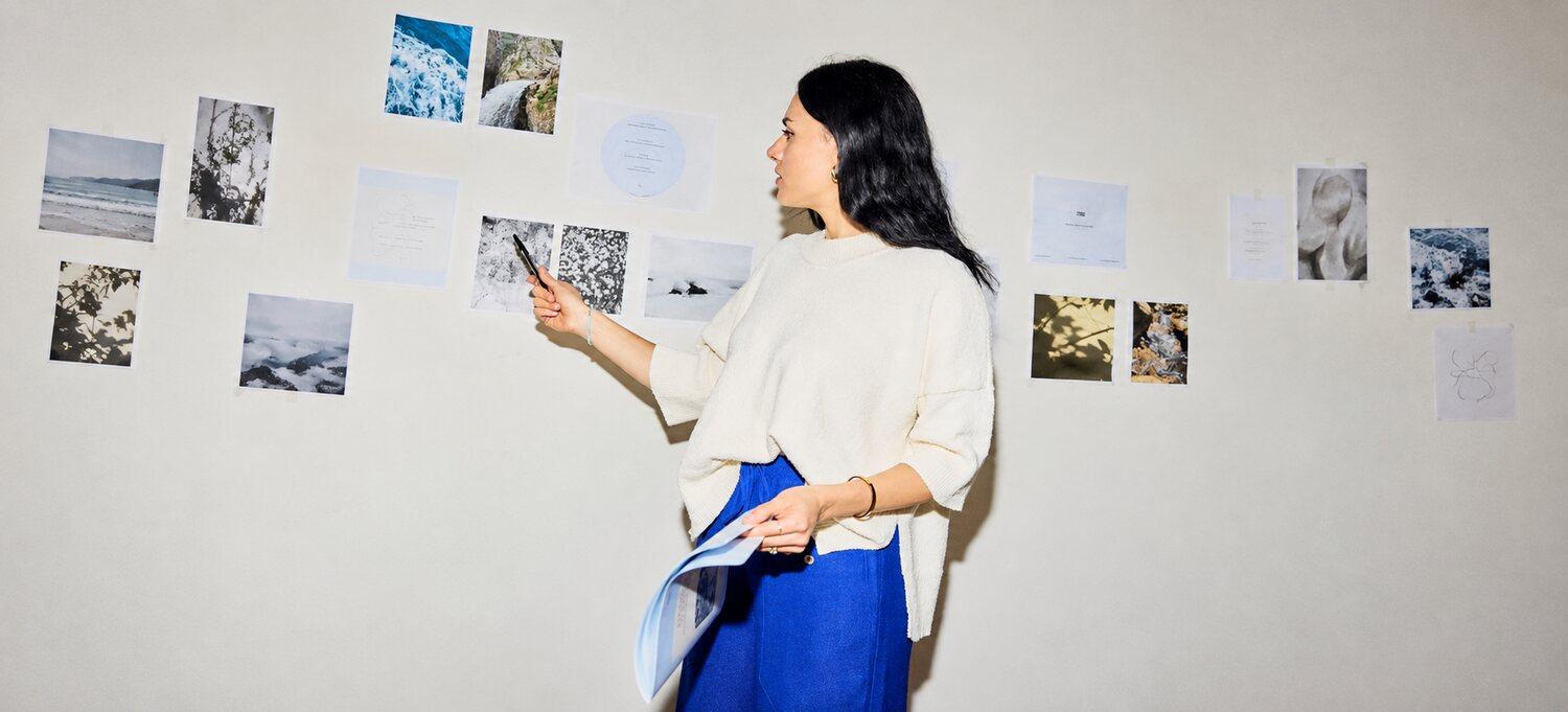 A woman organizing ideas and photographs on a studio wall