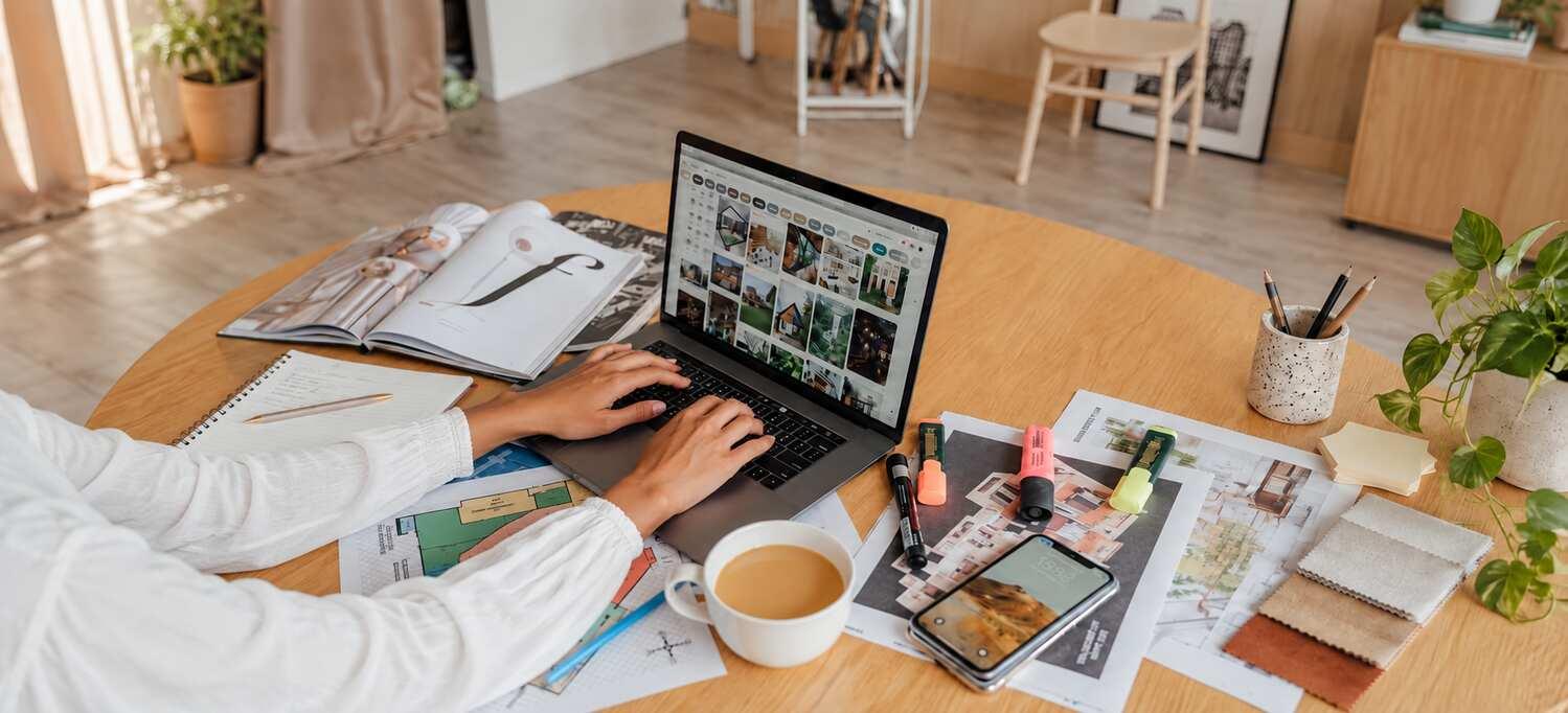 A creative professional working with a laptop, magazines, and a notebook