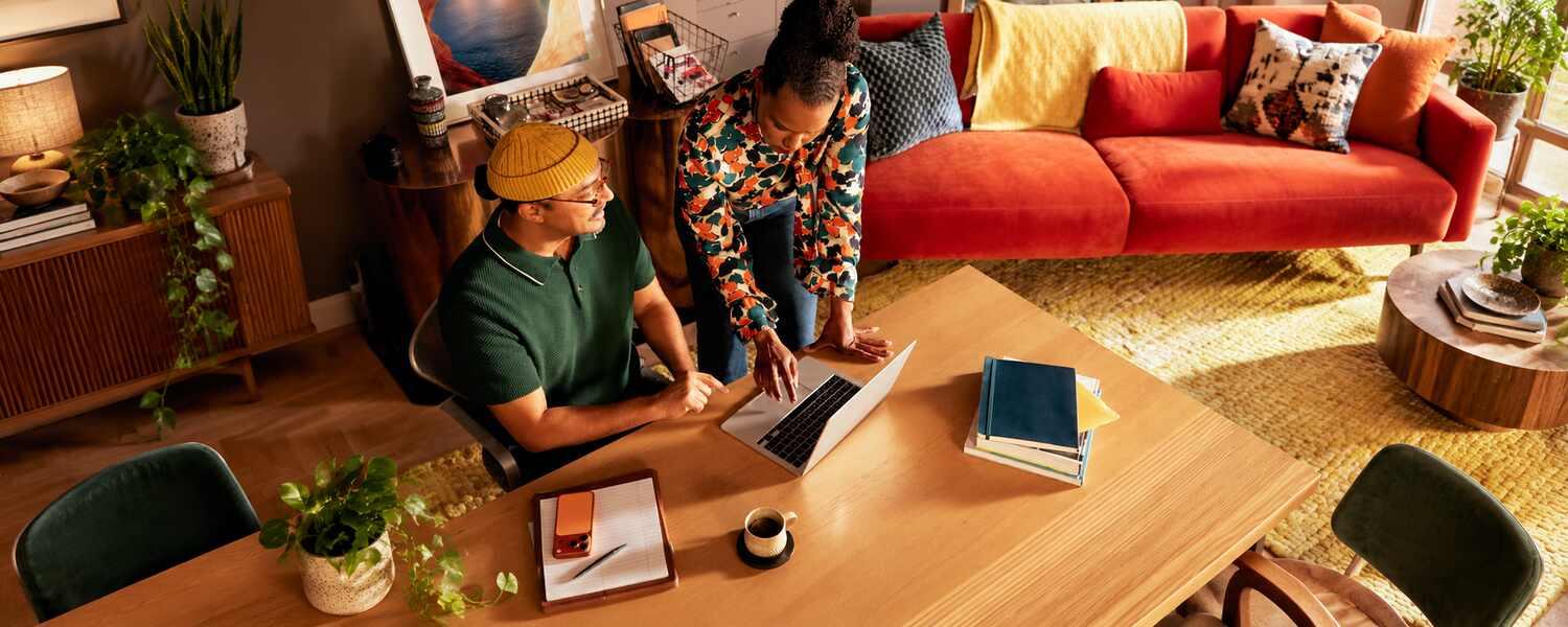 Two coworkers discussing their work around a laptop in a relaxed living room